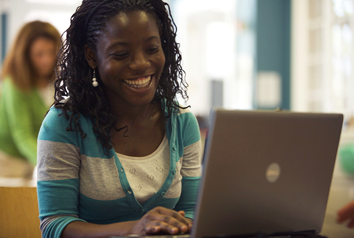 Framingham State University smiling while working on laptop